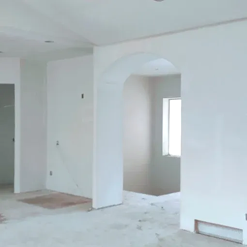 Interior of a room with white walls, an arched doorway, and a window. Concrete floor visible.