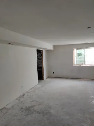 Empty room with white walls, exposed concrete floor, and a window.