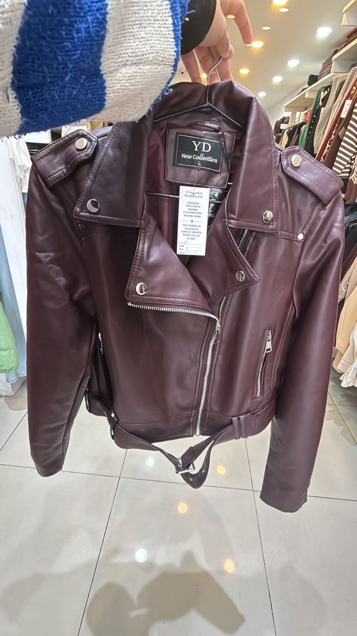 Chaqueta de motociclista color granate de piel sintética colgada en un perchero con etiqueta de precio.
