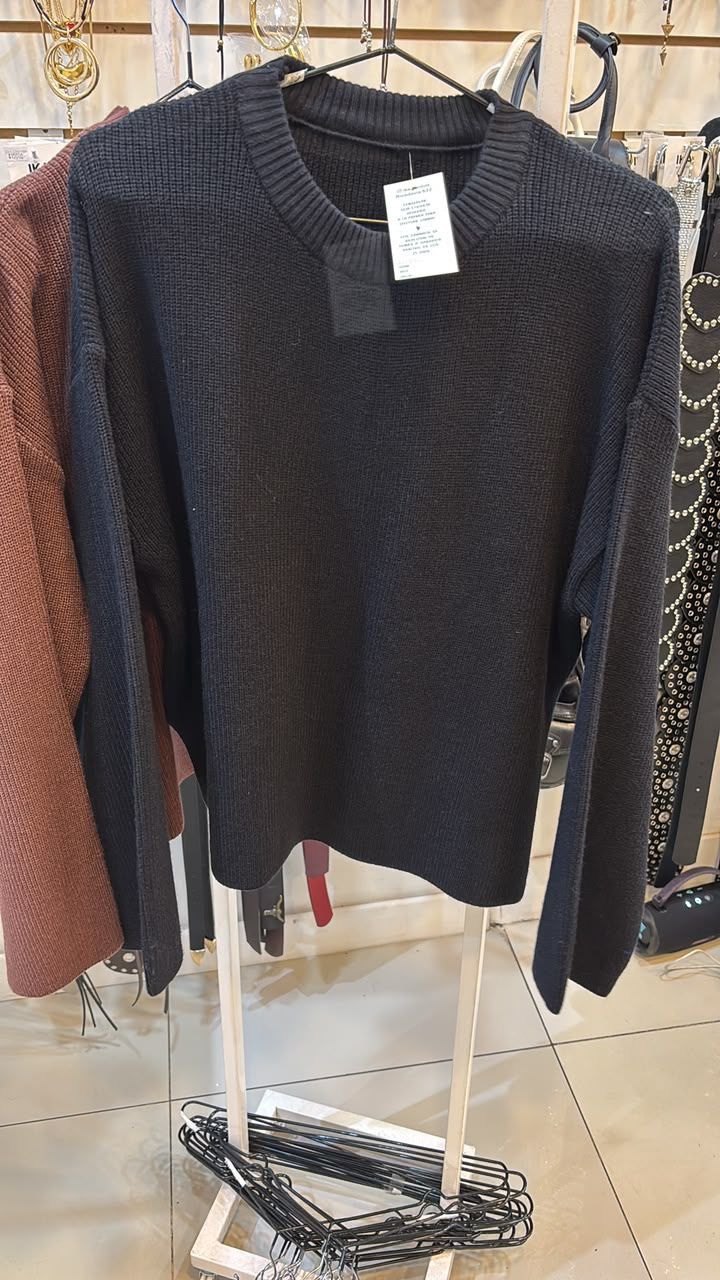 Un suéter de punto negro colgado en un perchero en una tienda.