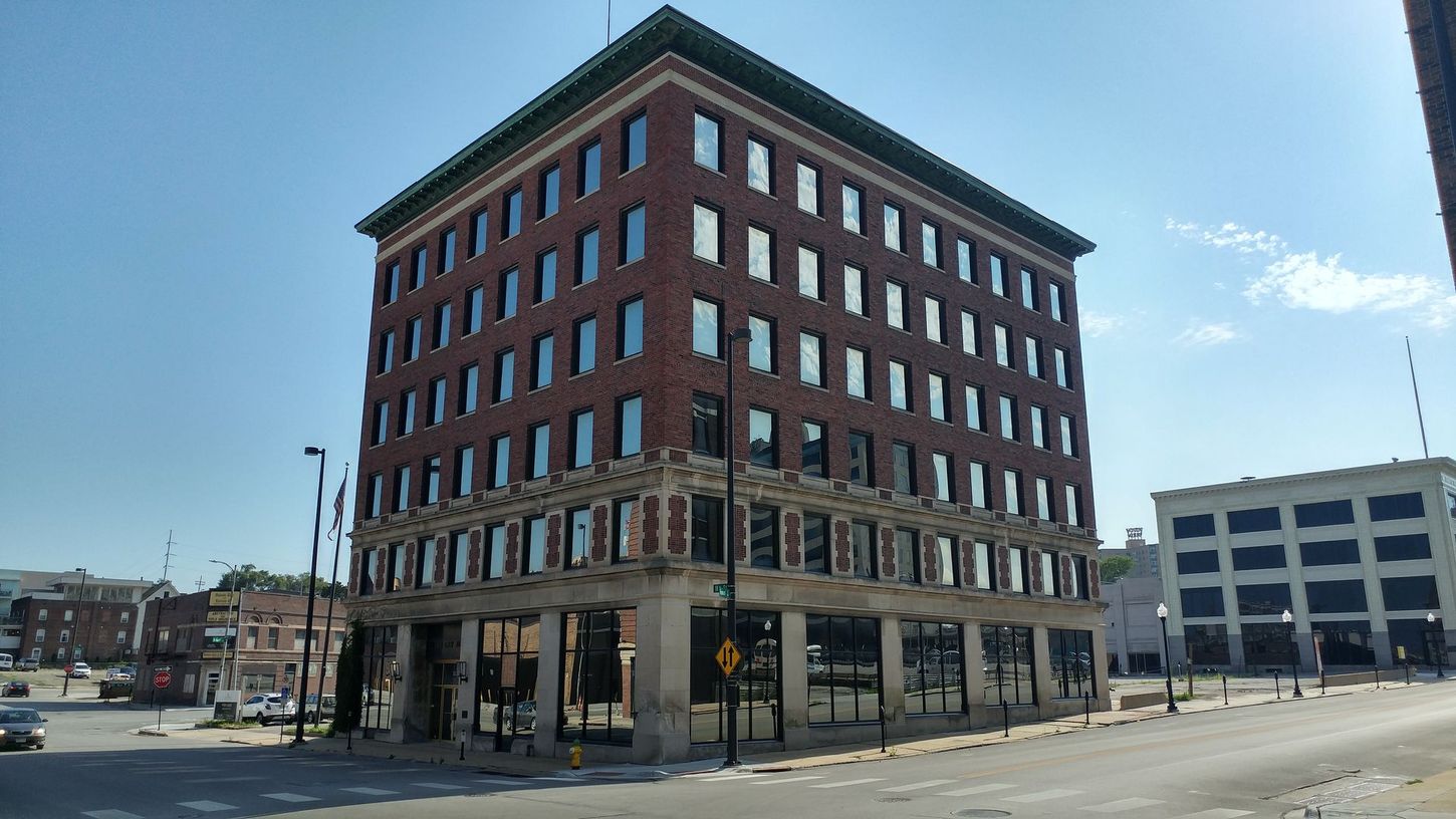 Corner brick office building on a city street under a clear blue sky