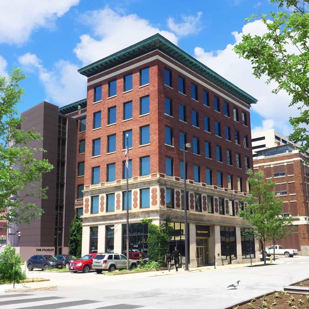 Brick mid-rise office building with large windows on a sunny city street under a blue sky