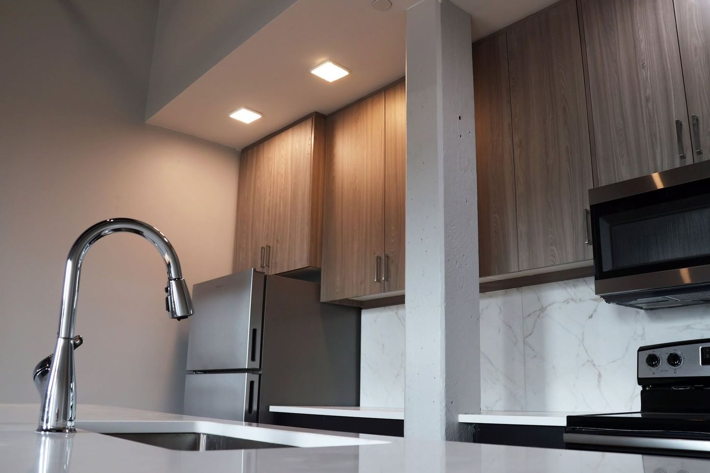 Modern kitchen with white island, chrome faucet, wood cabinets, and stainless steel appliances