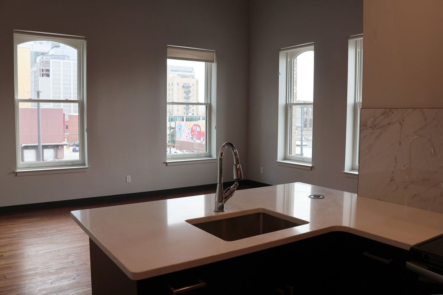 Modern kitchen with island sink and large windows overlooking a city street