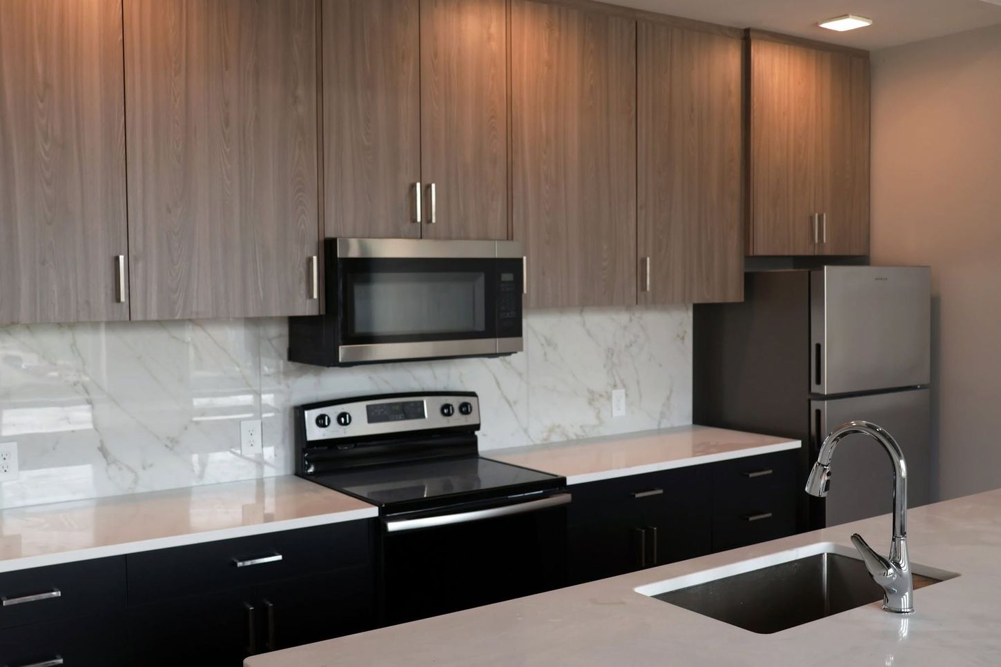 Modern kitchen with wood cabinets, black appliances, marble backsplash, and a sink island