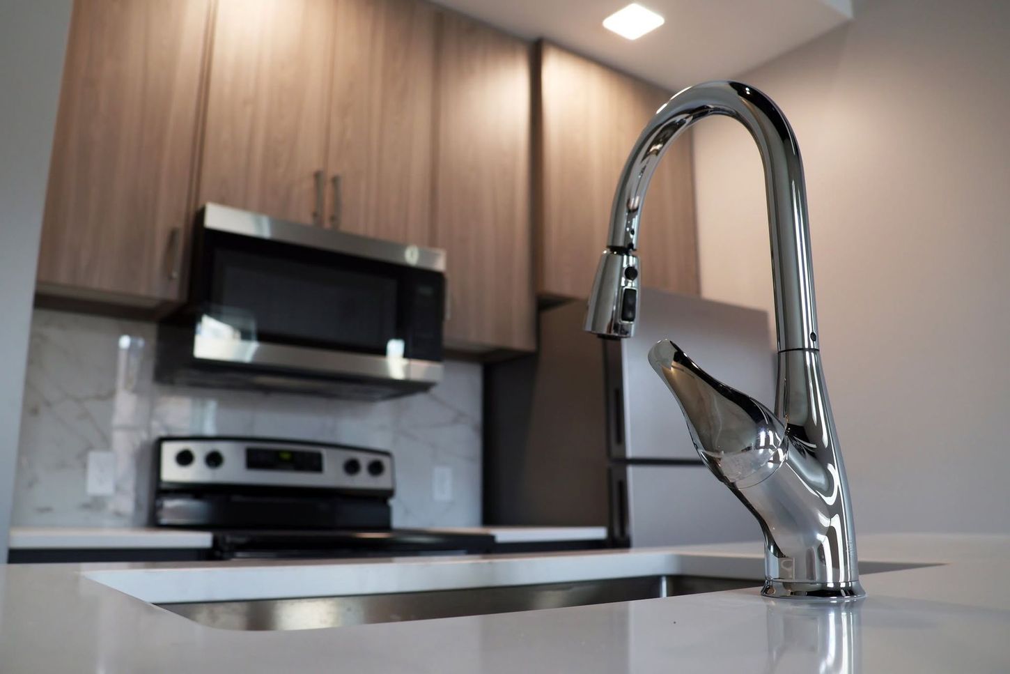 Modern kitchen with chrome faucet, stainless appliances, and wood cabinets