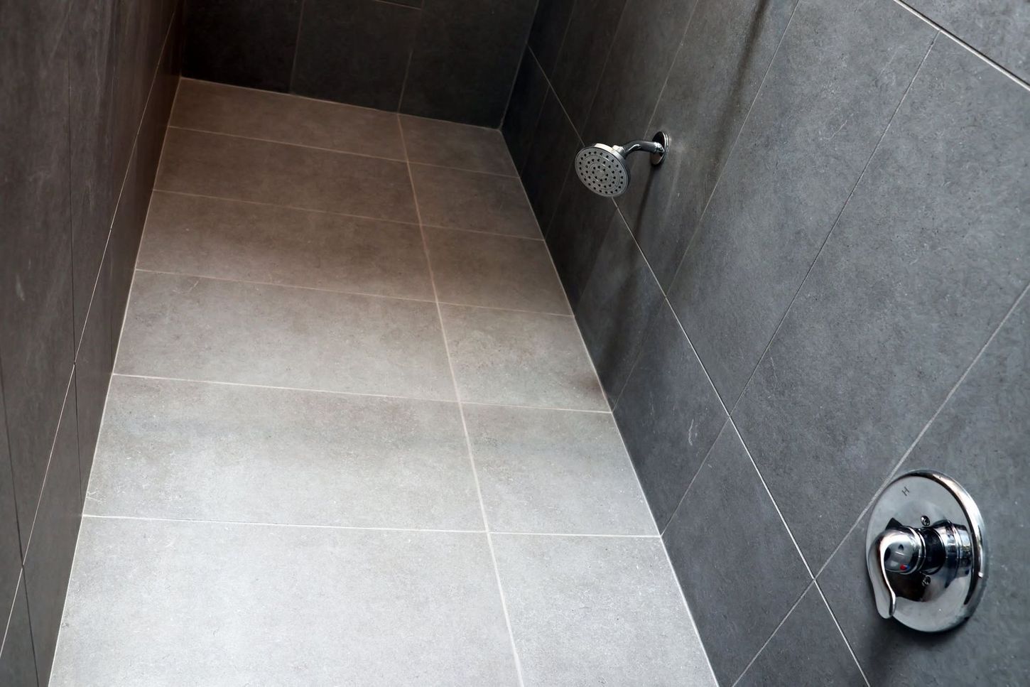 Empty tiled shower stall with gray walls and chrome fixtures