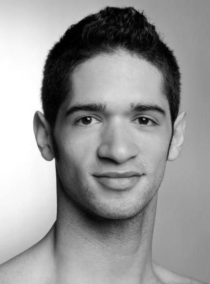 Black and white headshot of a young man with dark hair, smiling.