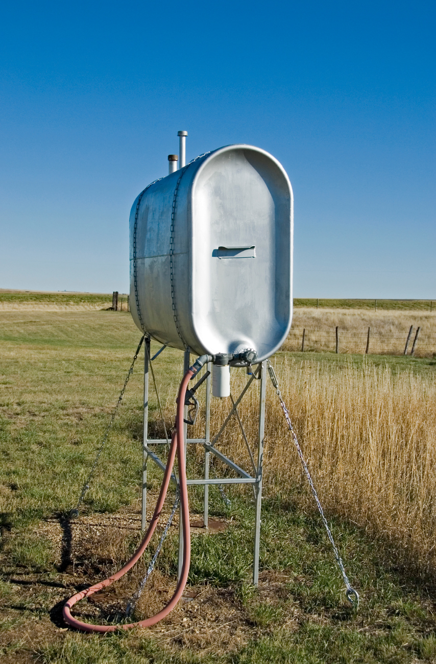 A large metal tank is sitting in the middle of a grassy field.
