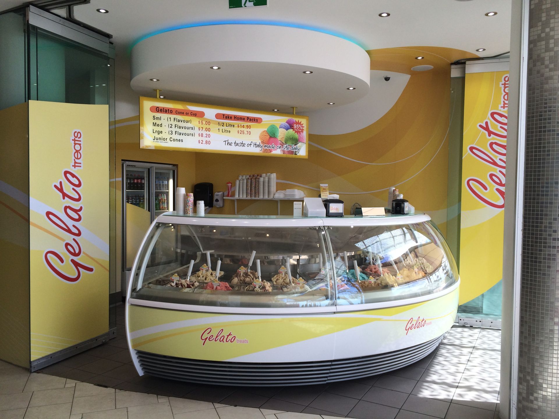 A Curved, Yellow Gelato Messina Kiosk in a Brightly Lit Indoor Space — Gray Projects in Woodford, QLD