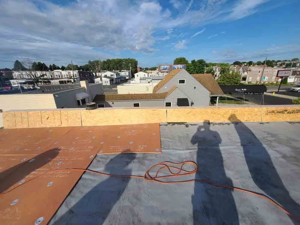 Rooftop with orange safety line, low building rooftops, and a blue sky with clouds in the background