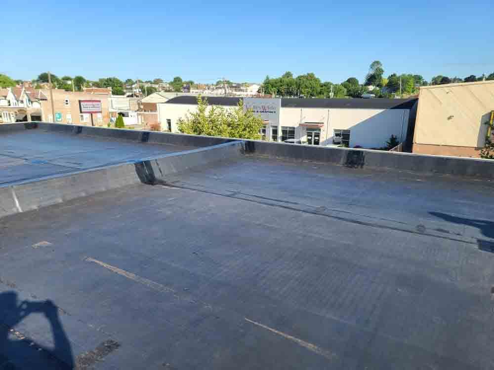 Flat rooftop overlooking storefronts under a clear blue sky.