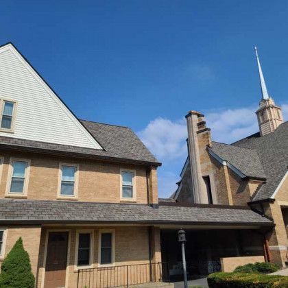Brick house and church steeple under a clear blue sky