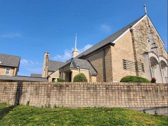 Stone church building behind a low wall under a clear blue sky