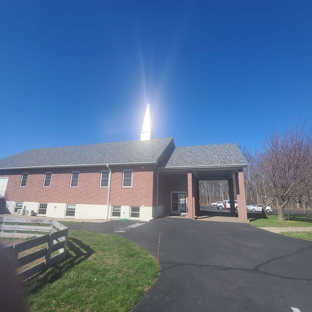 Red brick building with covered entrance and driveway under a clear blue sky