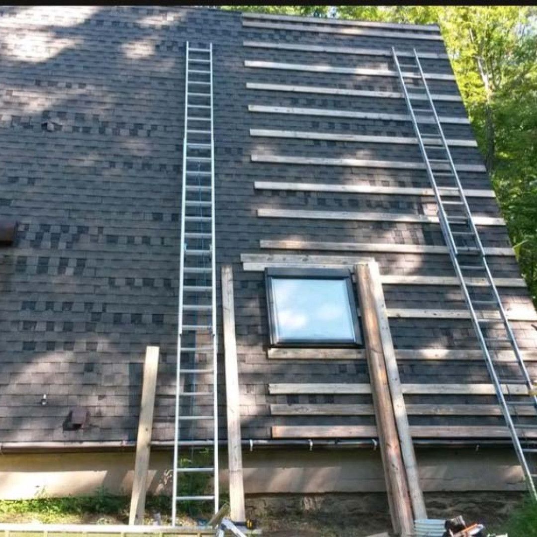 Ladders leaning against a dark wood building with a small window and sunlight casting shadows on the wall