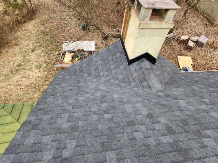 Gray shingled roof with a chimney and surrounding yard below
