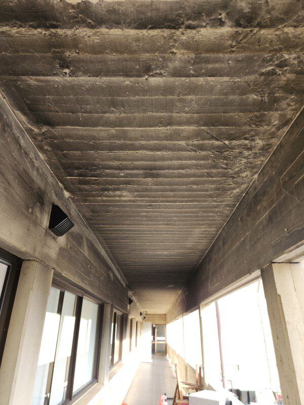 A long hallway with a concrete ceiling and a lot of windows.