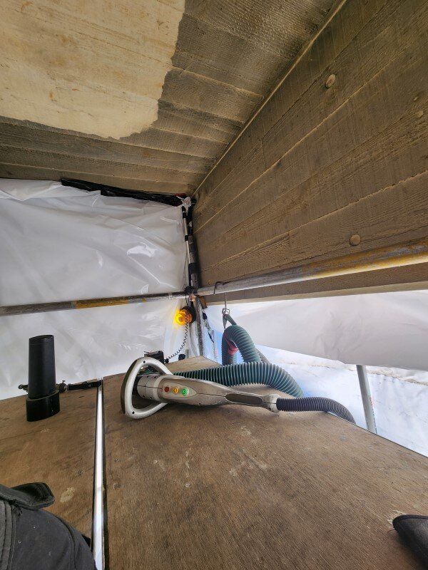 A person is standing in a room with a hose hanging from the ceiling.