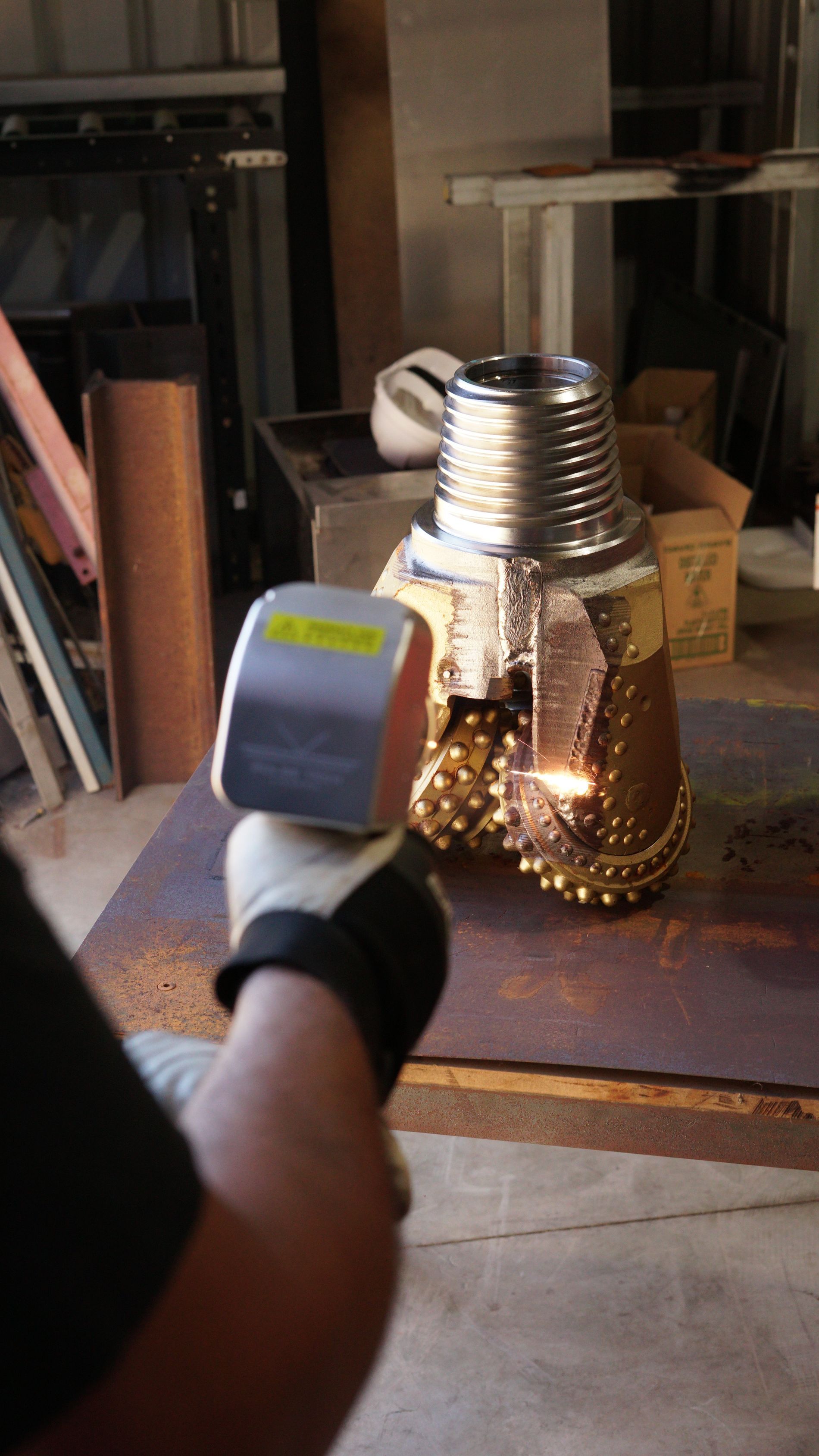 A person is holding a laser beam over a metal object.