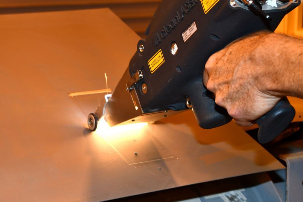 A person is using a laser to cut a piece of metal.