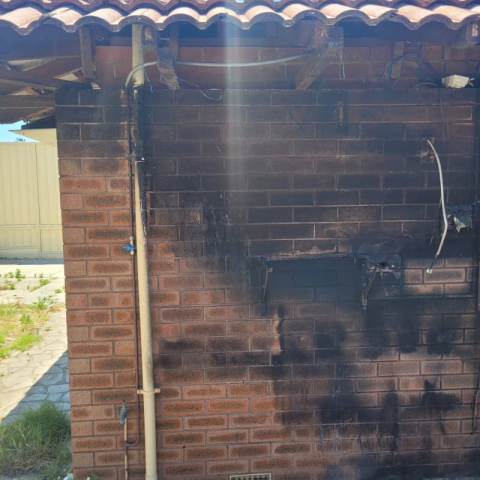A brick wall with a pipe coming out of it and a roof.