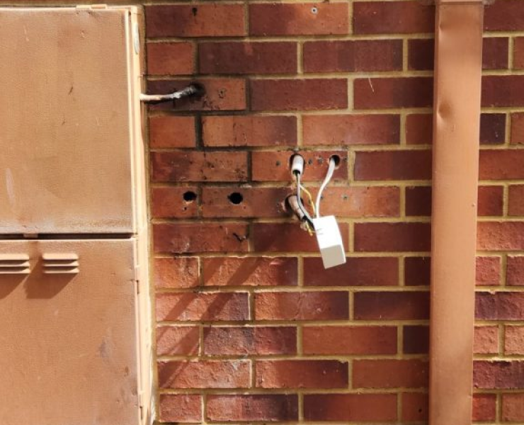 A brick wall with a few wires coming out of it