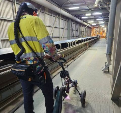 A man in a yellow safety vest is walking down a conveyor belt
