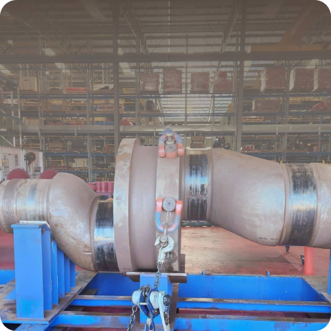 A large metal pipe is sitting on a blue stand in a factory.