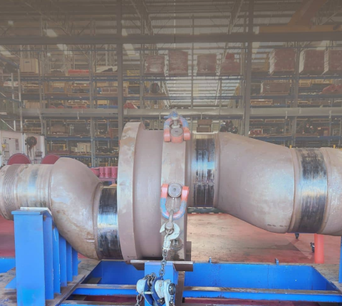A large pipe is sitting on top of a blue table in a factory.