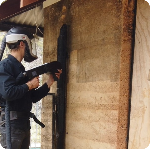A man wearing a welding helmet is working on a wall