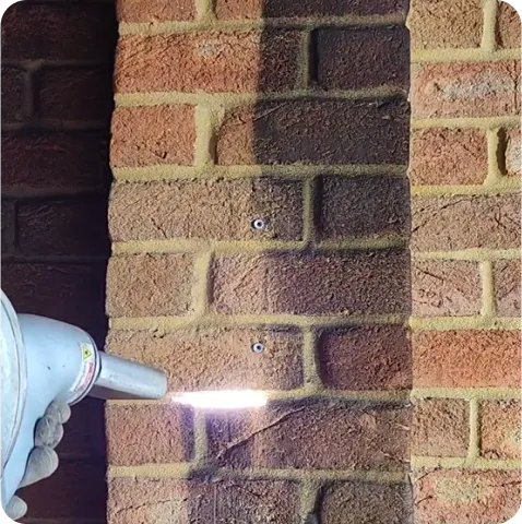 A person is spraying paint on a brick wall