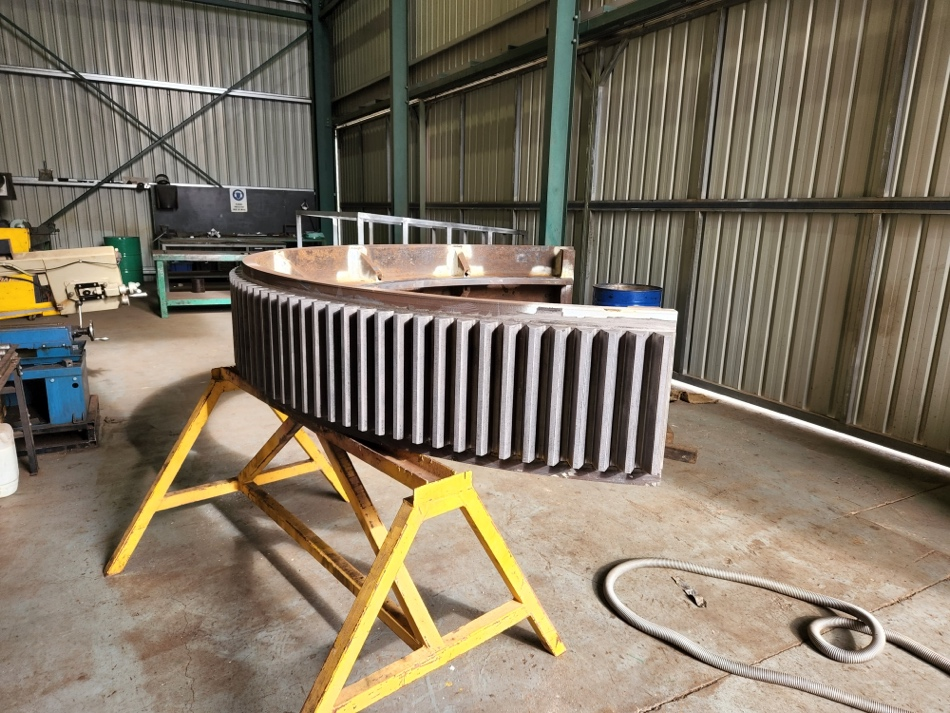 A large metal object is sitting on a yellow stand in a warehouse.