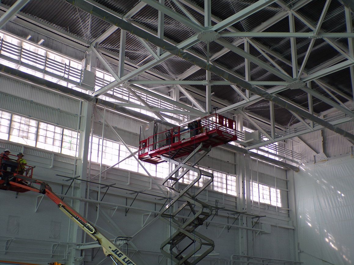 A group of people are working on the ceiling of a building.