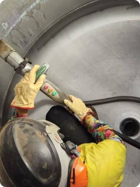 A person wearing yellow gloves is working on a machine