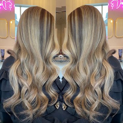 A woman with long blonde hair is standing in front of a mirror.