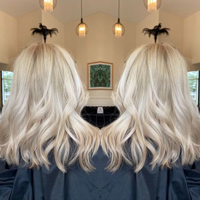 A woman with blonde hair is sitting in a chair in front of a mirror.