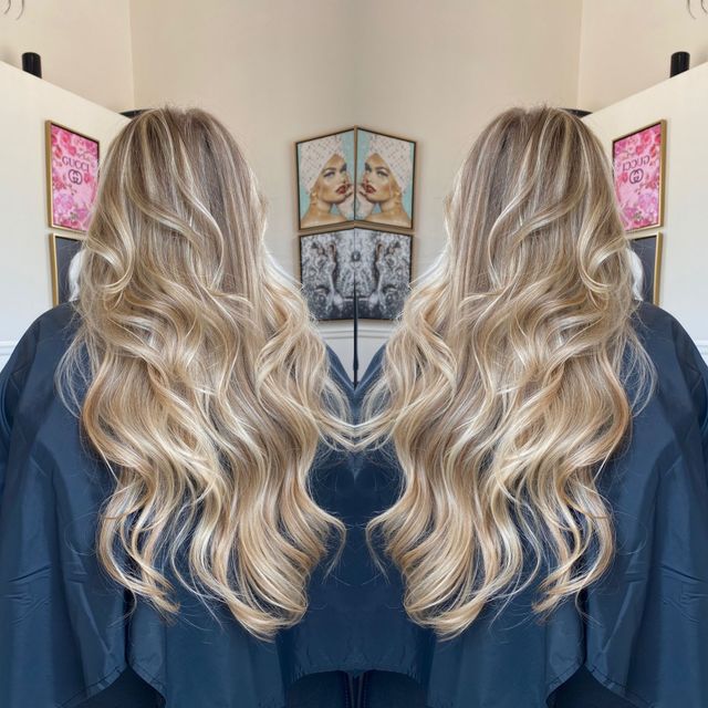 A woman with long blonde hair is standing in front of a mirror.