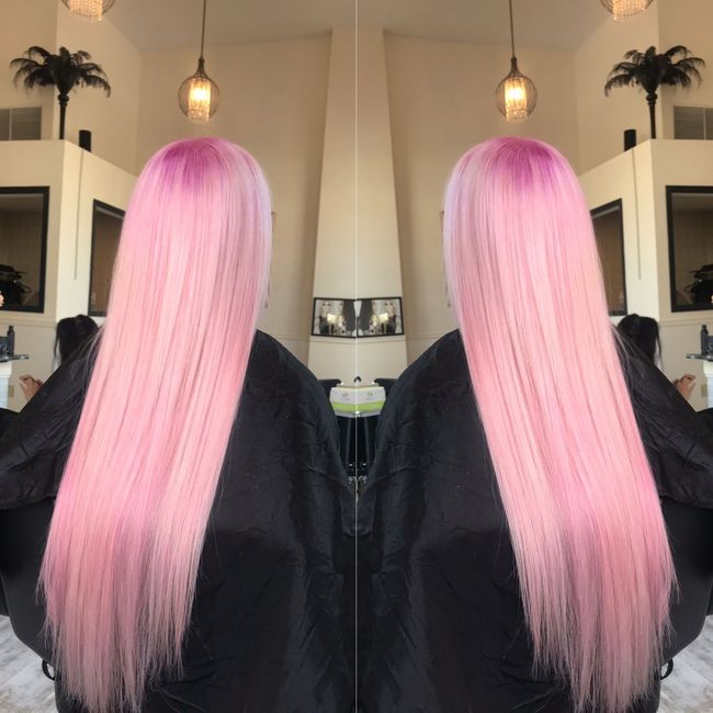 A woman with long pink hair is getting her hair cut