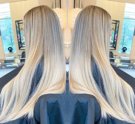 A woman with long blonde hair is sitting in front of a mirror.