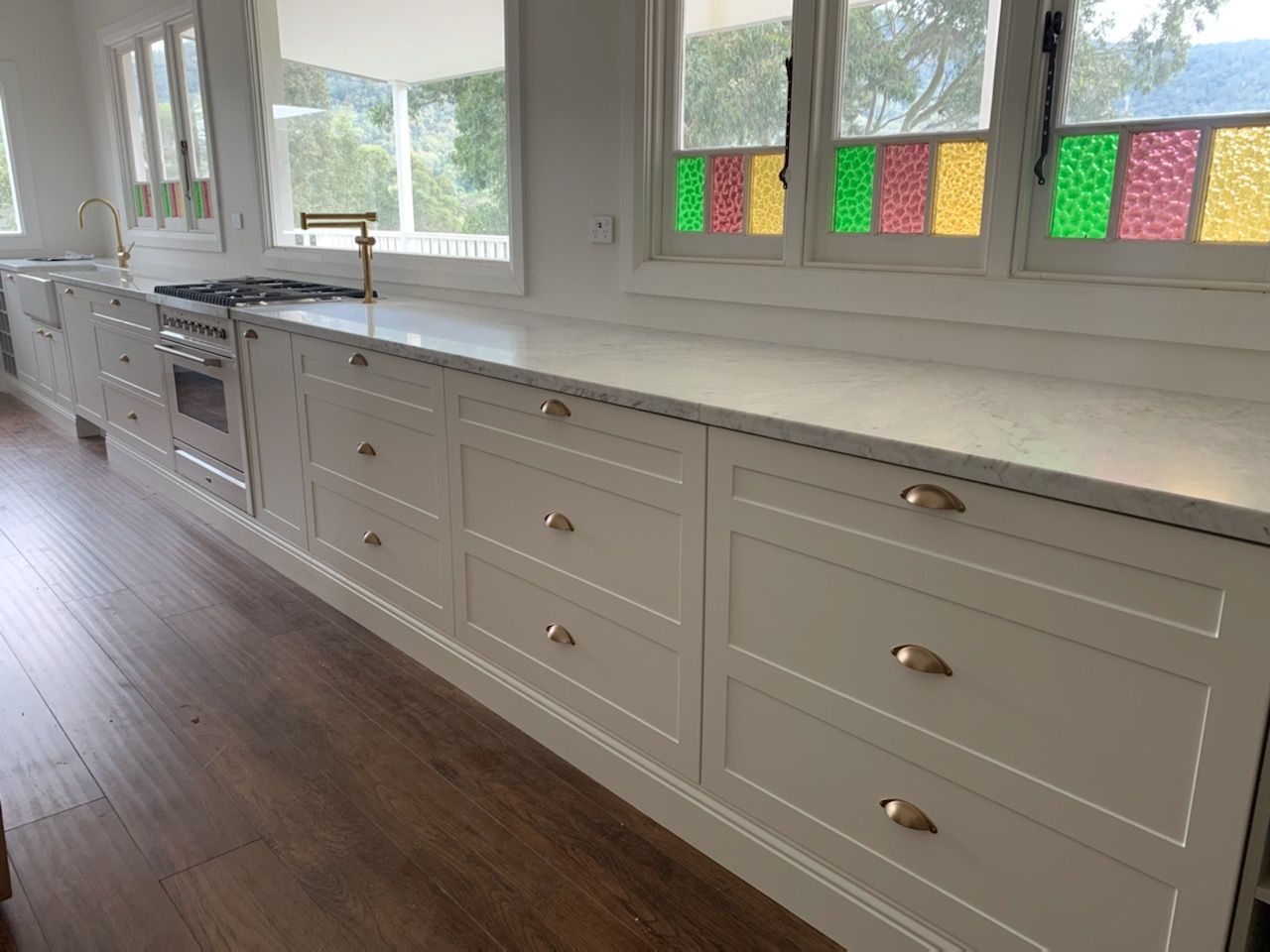 A Long White Kitchen Bench with white cabinets — Tefa Kitchens & Joinery in Maitland, NSW