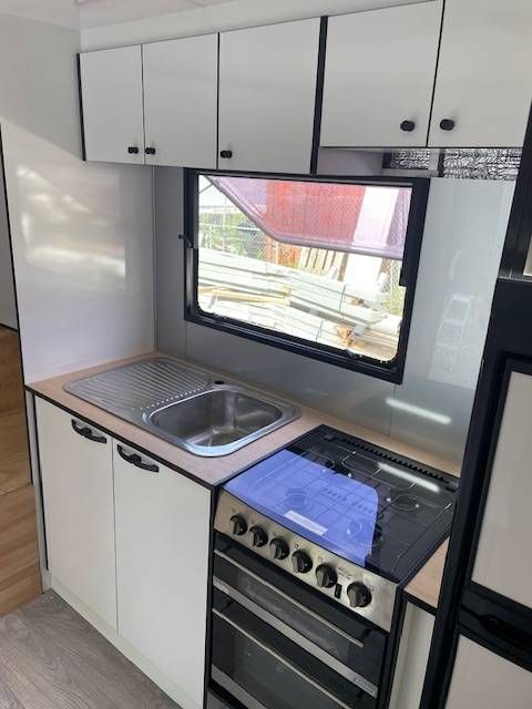 A Kitchen With White Cabinets And Black Handles And A Sink — Tefa Kitchens & Joinery in Rutherford, NSW