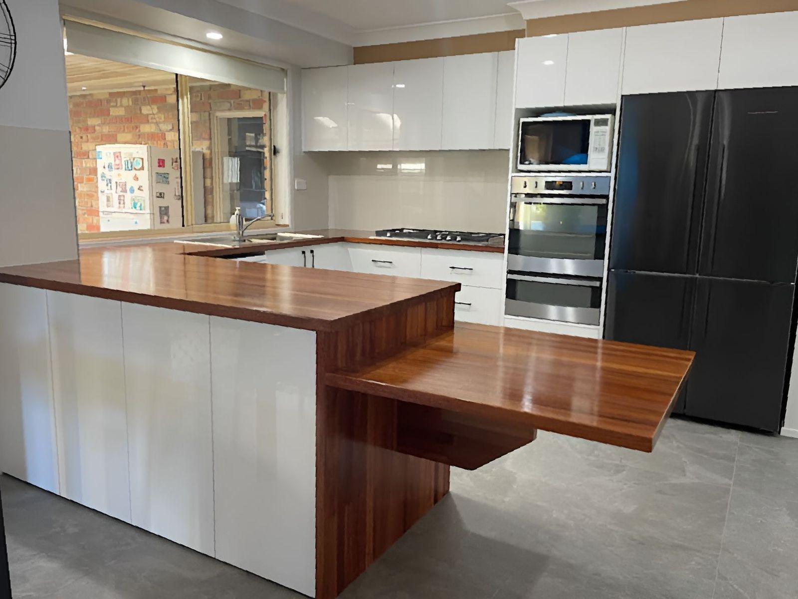 A Kitchen With a Wooden Island and White Cabinets — Tefa Kitchens & Joinery in Rutherford, NSW