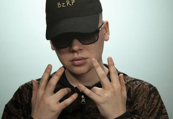 Hombre que lleva gafas de sol y gorra, haciendo un gesto con la mano.