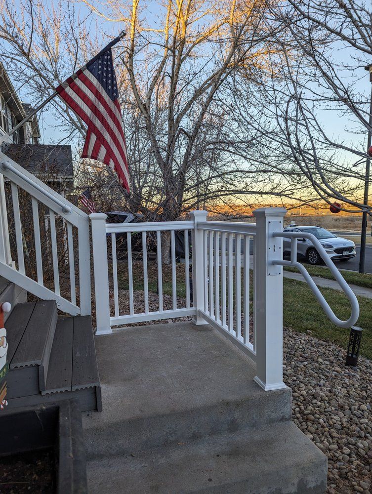 Black metal railing with stairs leading to a backyard with brown wooden fence and green grass.