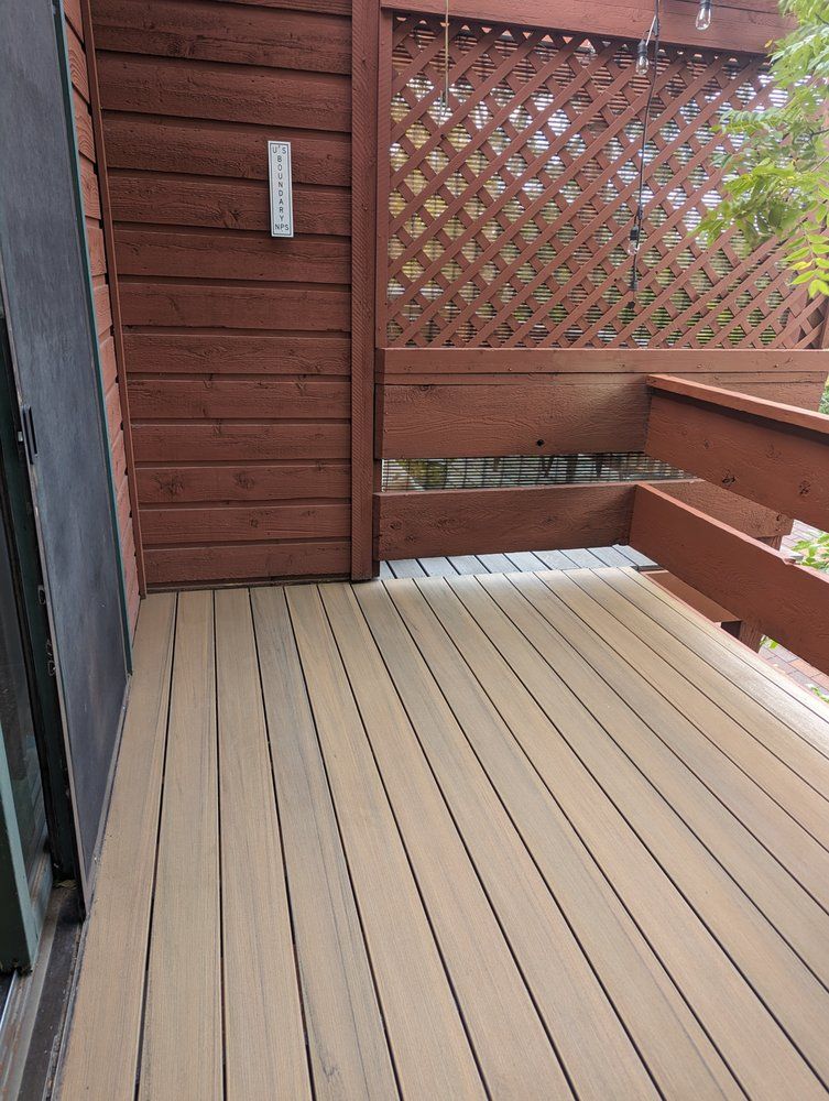 Wooden deck with brown lattice and railing against a brown wooden wall; thermometer present.