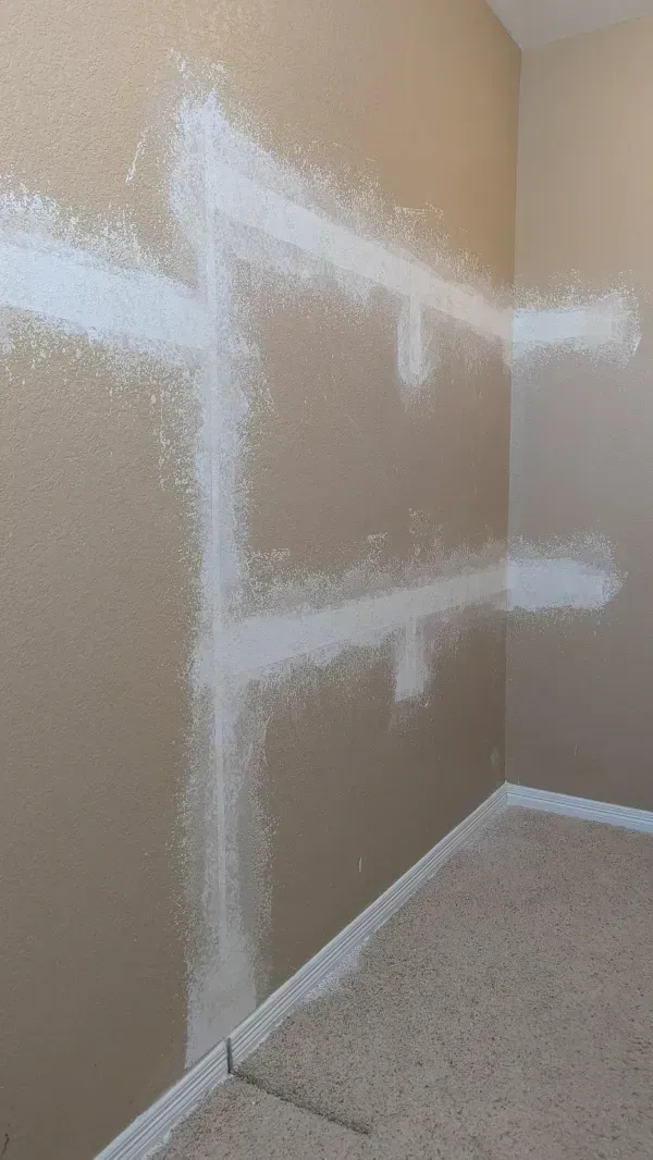 White drywall compound on beige wall in corner of room, near carpet.