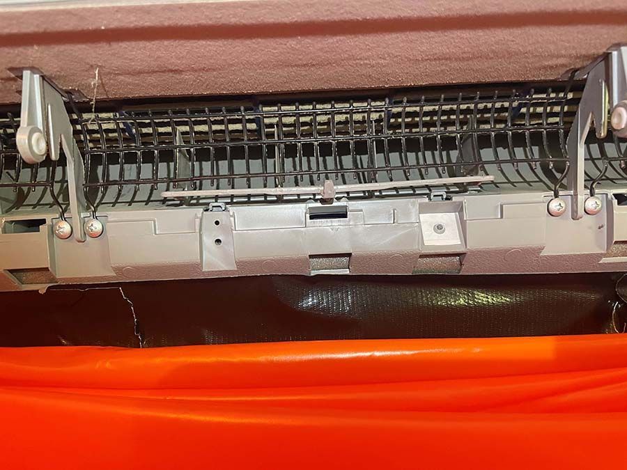 A close up of a machine with a red bucket in the background