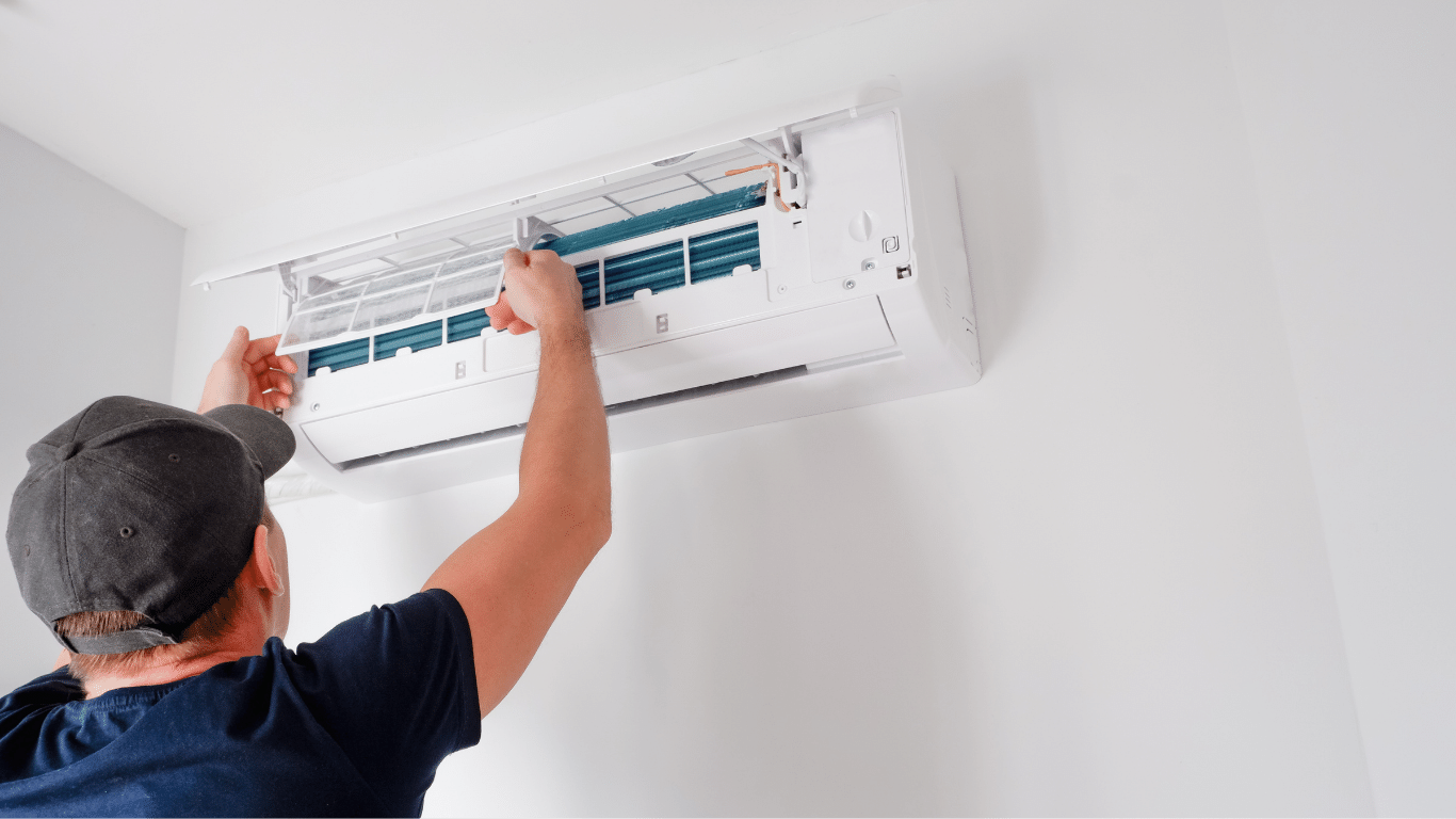 A man is installing an air conditioner on a wall.