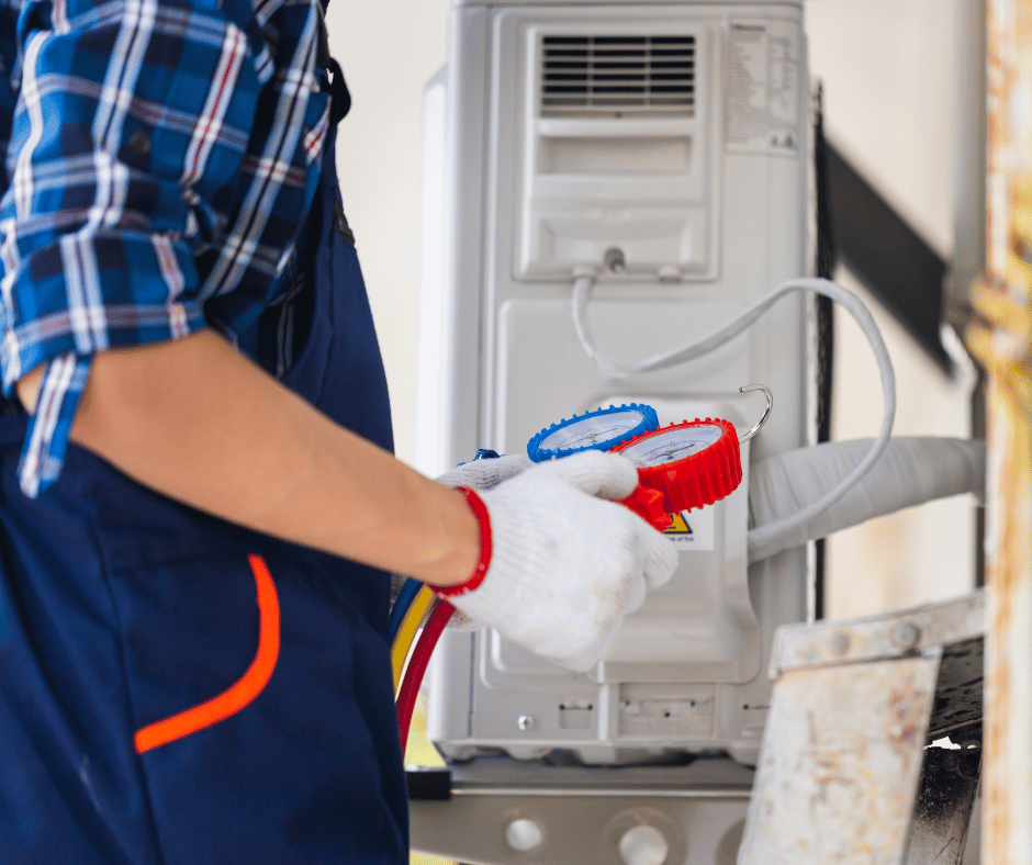 A man in a blue apron is working on an air conditioner.